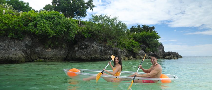 Guests kayaking in clear turquoise waters near the limestone cliffs and tropical shoreline of Amorita Resort in Panglao, Bohol