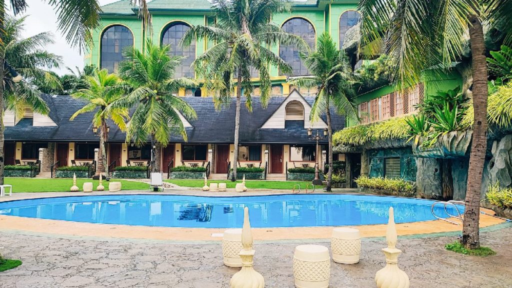 Swimming pool surrounded by palm trees and resort buildings at Bohol Tropics Resort in Tagbilaran City, Bohol