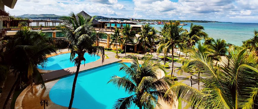 Bohol Tropics Resort in Tagbilaran City with palm-lined swimming pool, tropical villas, and ocean views along the Bohol coastline