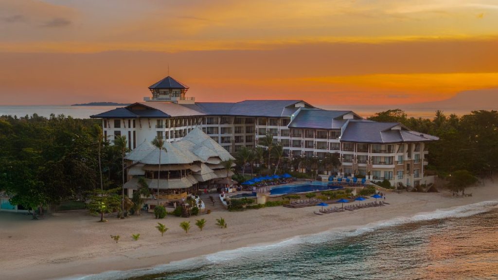 Bellevue Hotel Bohol beachfront resort with swimming pool, palm trees, and ocean view at sunset