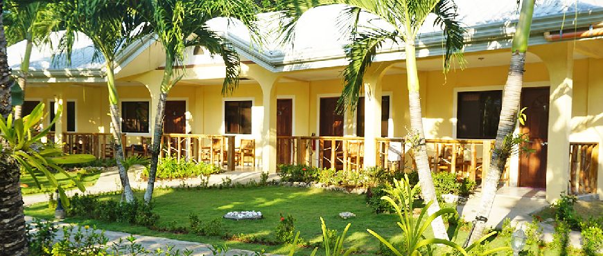 Bohol Sunside Resort with yellow cottages, private balconies, palm trees, and a landscaped tropical garden