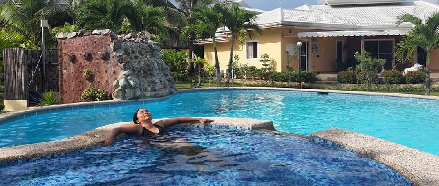 Swimming pool at Bohol Sunside Resort with palm trees, tropical landscaping, and resort villas in the background