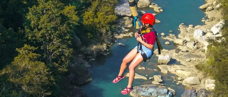Tourist enjoying a zipline ride at Danao Adventure Park in Bohol above a clear river and rocky canyon